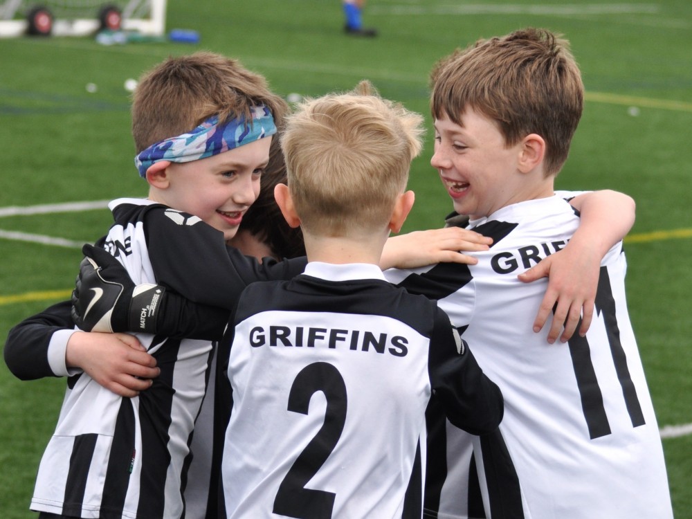 Junior team wearing black and white kits smiling and in a huddle