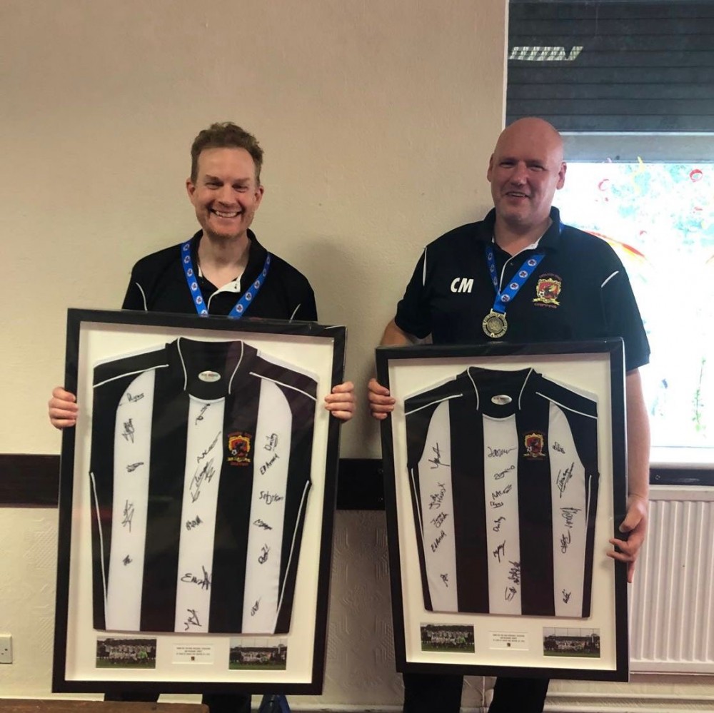 two people holding framed shirts..