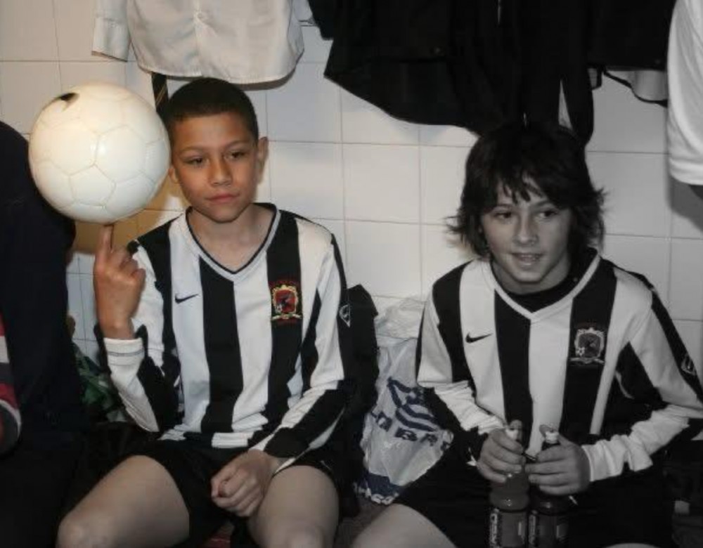 Two boys sitting down one with a ball